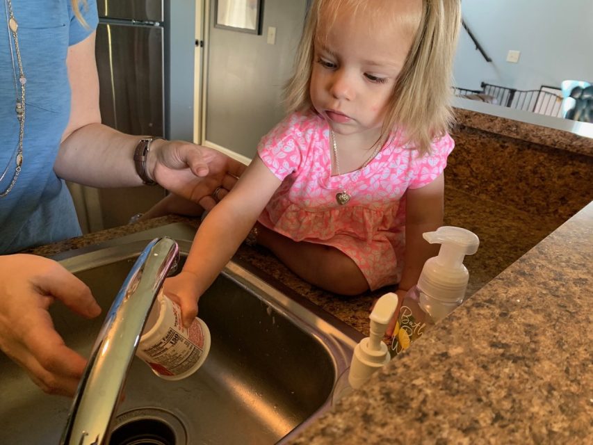 Little girl helping rinse yogurt container