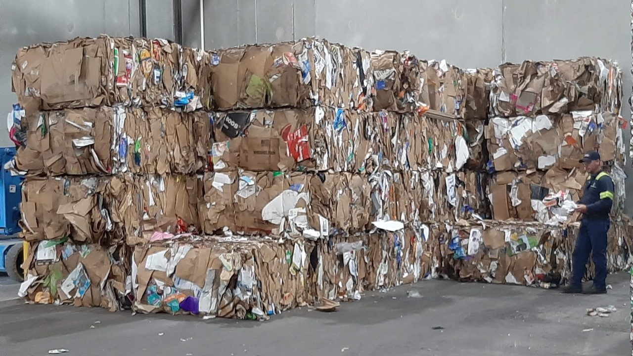 Flattened cardboard compressed into cubes, stacked and ready to be picked up for recycling