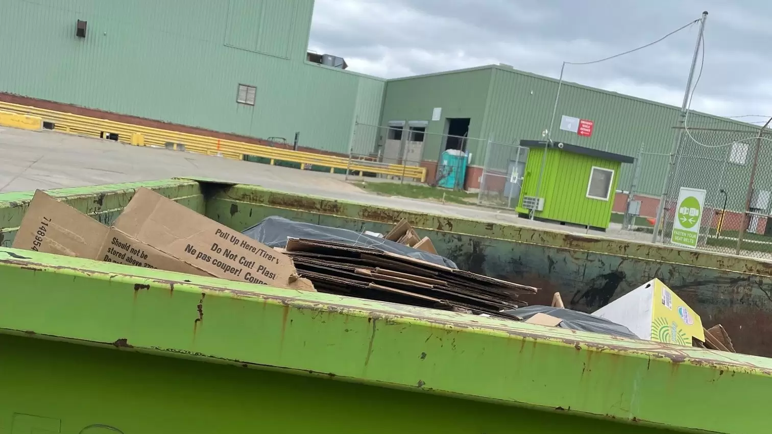 Container with trash sitting next to a large building
