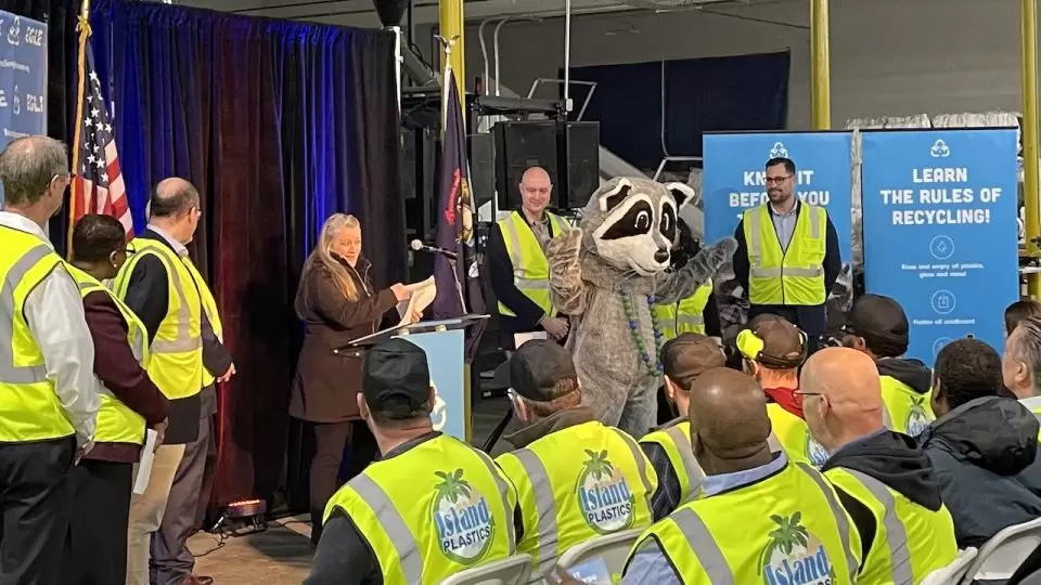 People wearing work vests sitting around listening to a speaker on podium