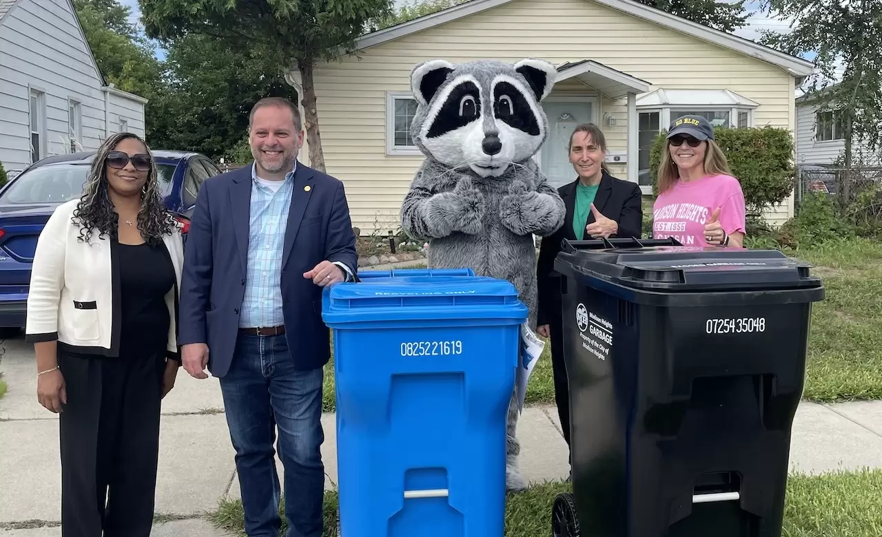 People standing around a trash bin