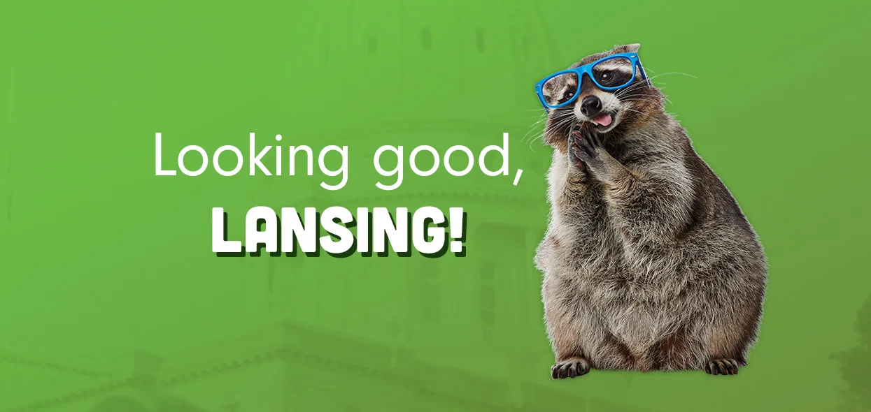 Looking good, Lansing! &mdash; a raccoon in blue sunglasses against green, over a faded photo of the Michigan Capitol.